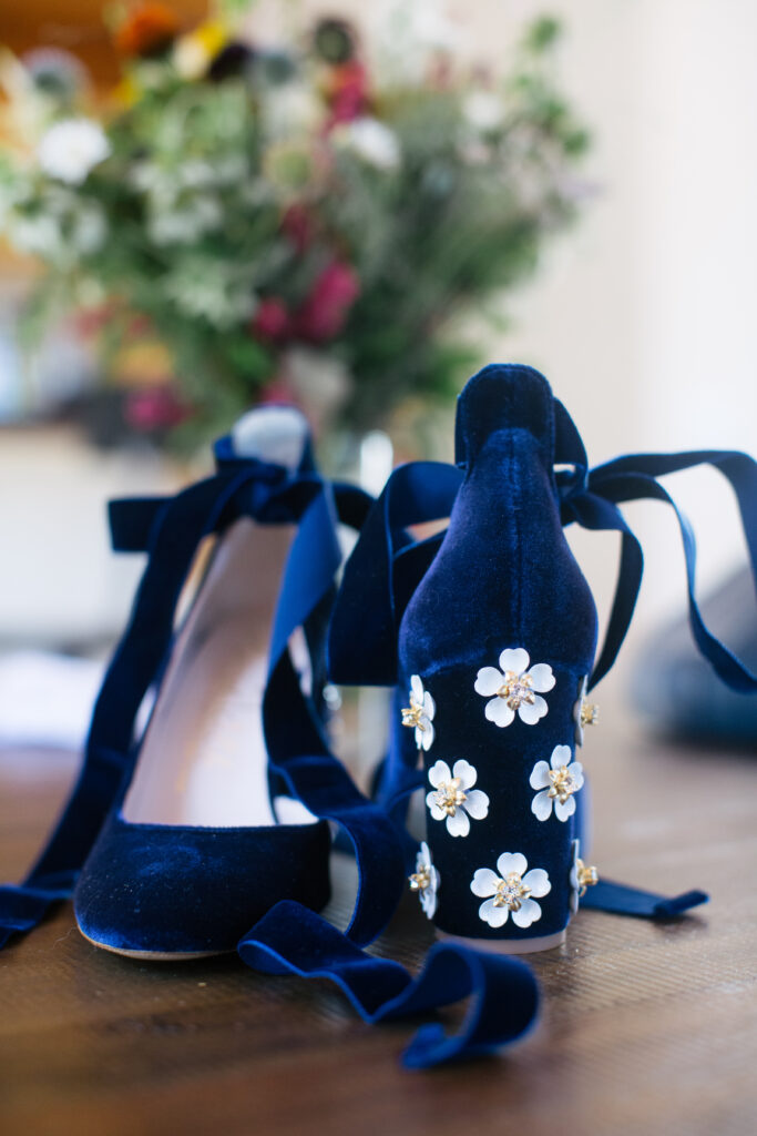 Royal blue velvet heels with metal white daisies on the heel and ribbons to tie around the ankles.