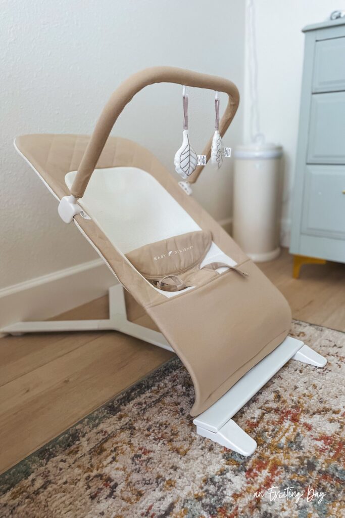 Baby bouncer with tan and cream fabric.