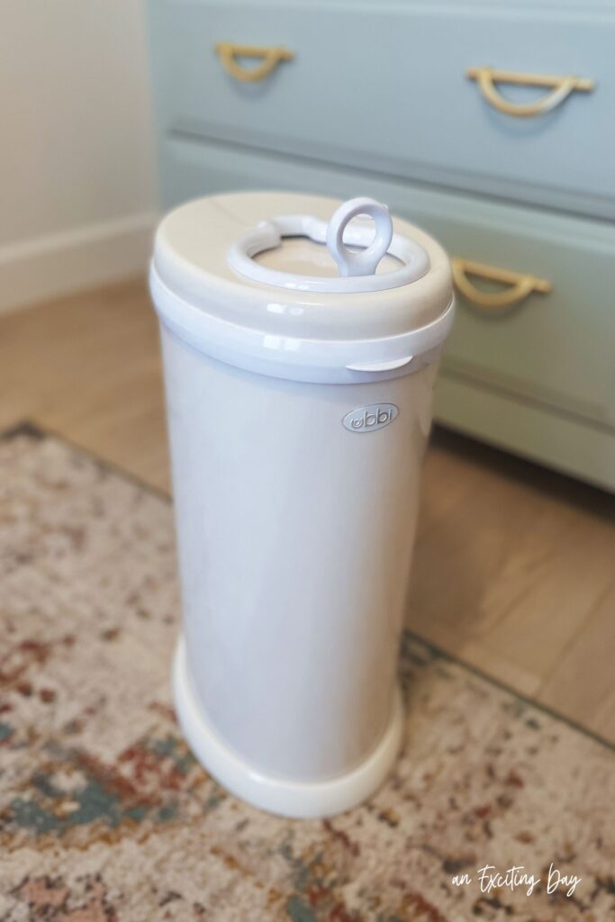 Cream and white diaper pail with the brand "ubbi" on the front.