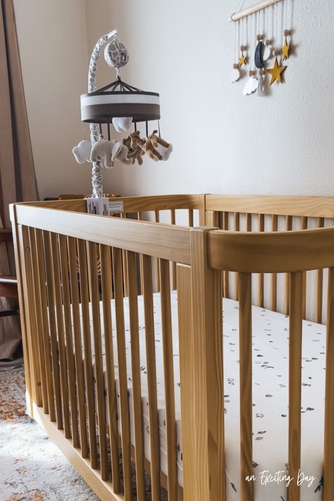 Wooden baby crib with a mobile above it.