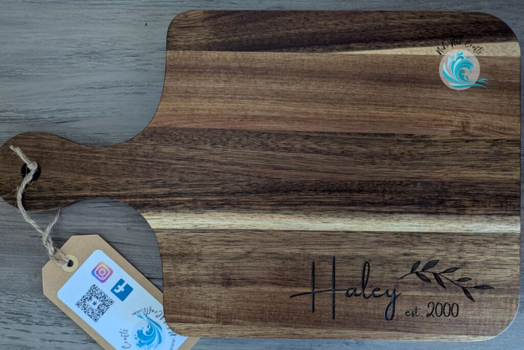 Acacia wood cutting board with "Haley est. 2000" engraved near one edge.