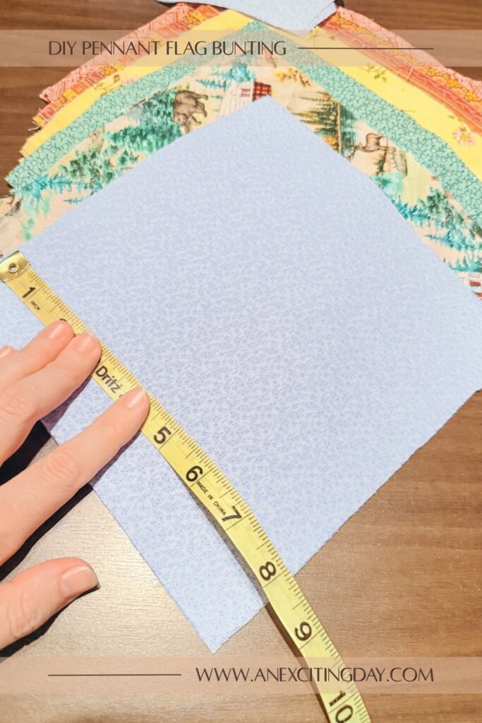 Stacks of fabric squares in a variety of colors with blue on top and a measuring tape showing the square is 8 inches across. Overlay text reads "diy pennant flag bunting: and "www.anexcitingday.com".