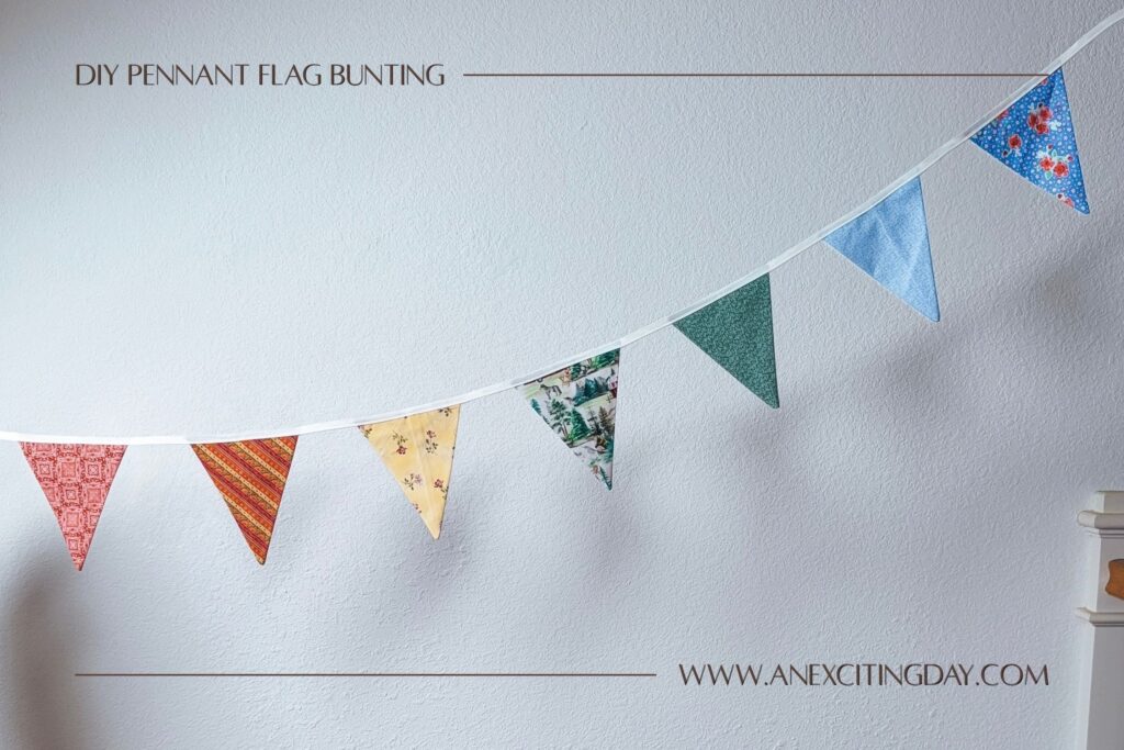 Colorful pennant flag bunting with red, orange stripe, yellow floral, green print, green floral, and blue floral fabrics strung in front of a white textured wall. Overlay text reads "diy pennant flag bunting: and "www.anexcitingday.com".