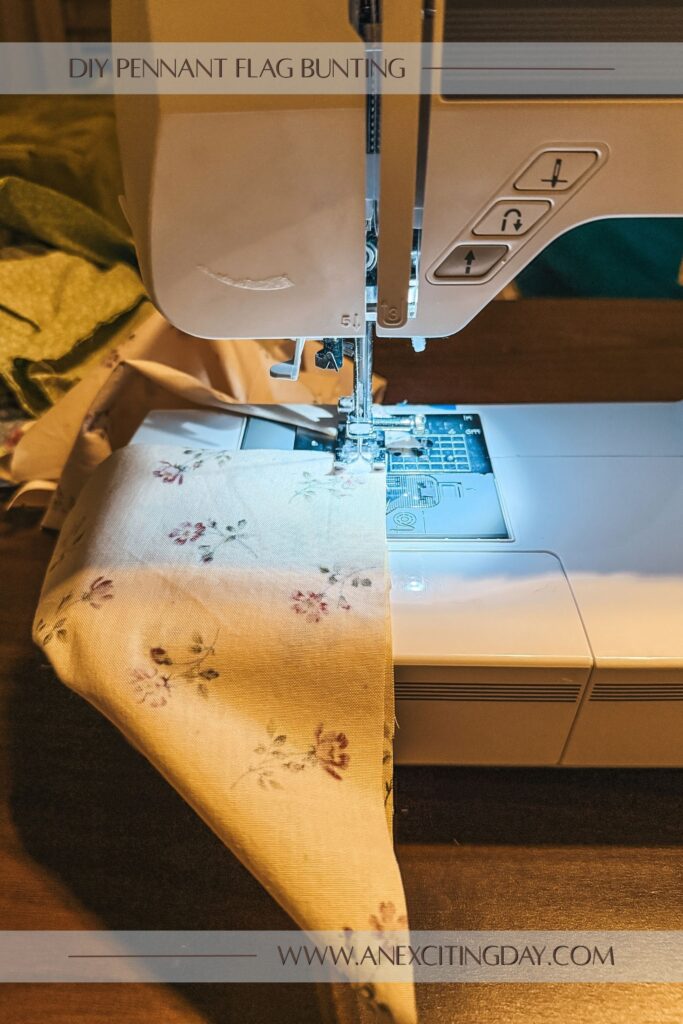 Sewing project scene with yellow floral fabric in a triangle shape passing through a sewing machine. Overlay text reads "diy pennant flag bunting: and "www.anexcitingday.com".