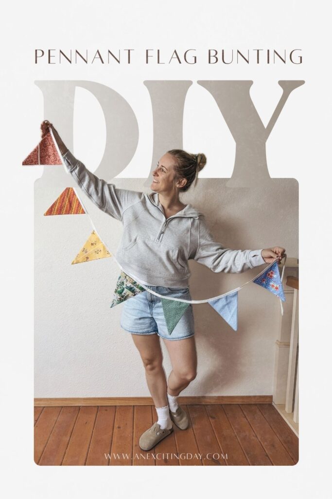 Woman in grey suede clogs, a grey hooded sweatshirt and light wash denim shorts holding a colorful pennant flag bunting. Overlay text reading "pennant flag bunting DIY" and "www.anexcitingday.com".