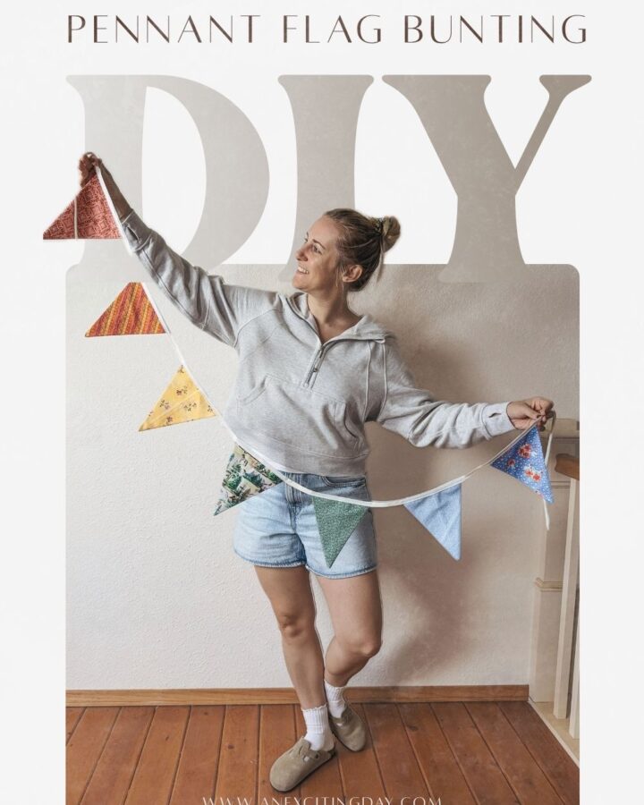 Woman in grey suede clogs, a grey hooded sweatshirt and light wash denim shorts holding a colorful pennant flag bunting. Overlay text reading "pennant flag bunting DIY" and "www.anexcitingday.com".
